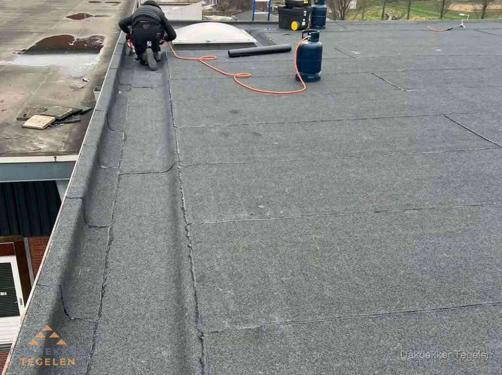 Dakdekker repareert bitumen dakbedekking op groot plat dak in Tegelen